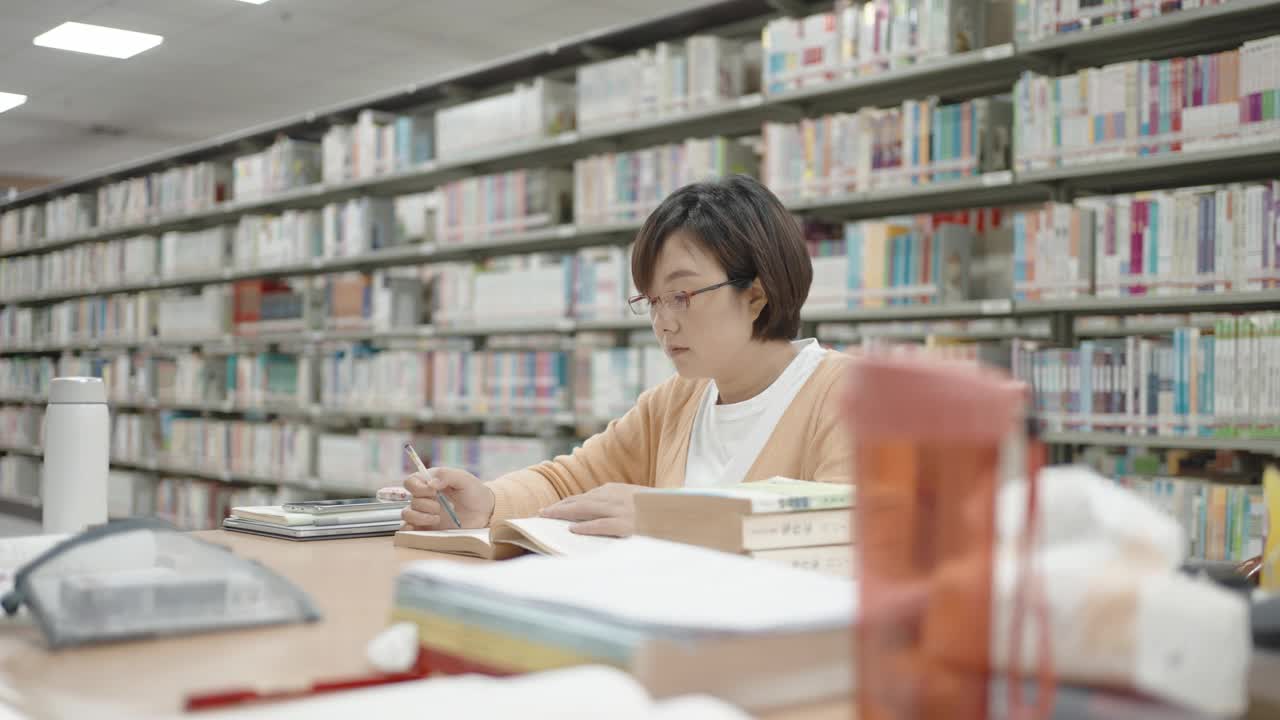 亚洲妇女在图书馆阅读和学习视频下载
