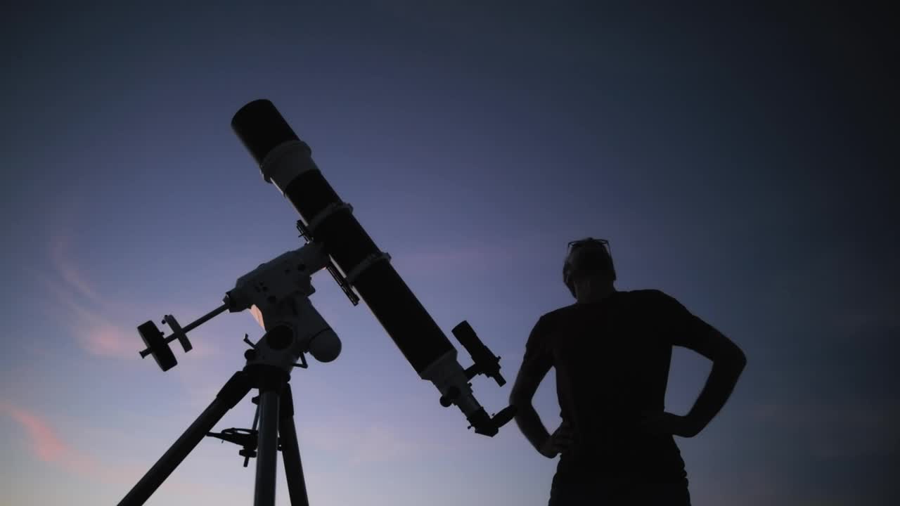 一个人的剪影，望远镜和夜空。业余天文学的概念。视频素材
