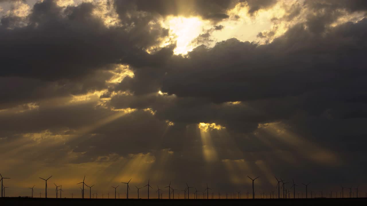 美国德克萨斯州罗斯科，日出时，阳光透过云层照射在风力发电场上方视频下载