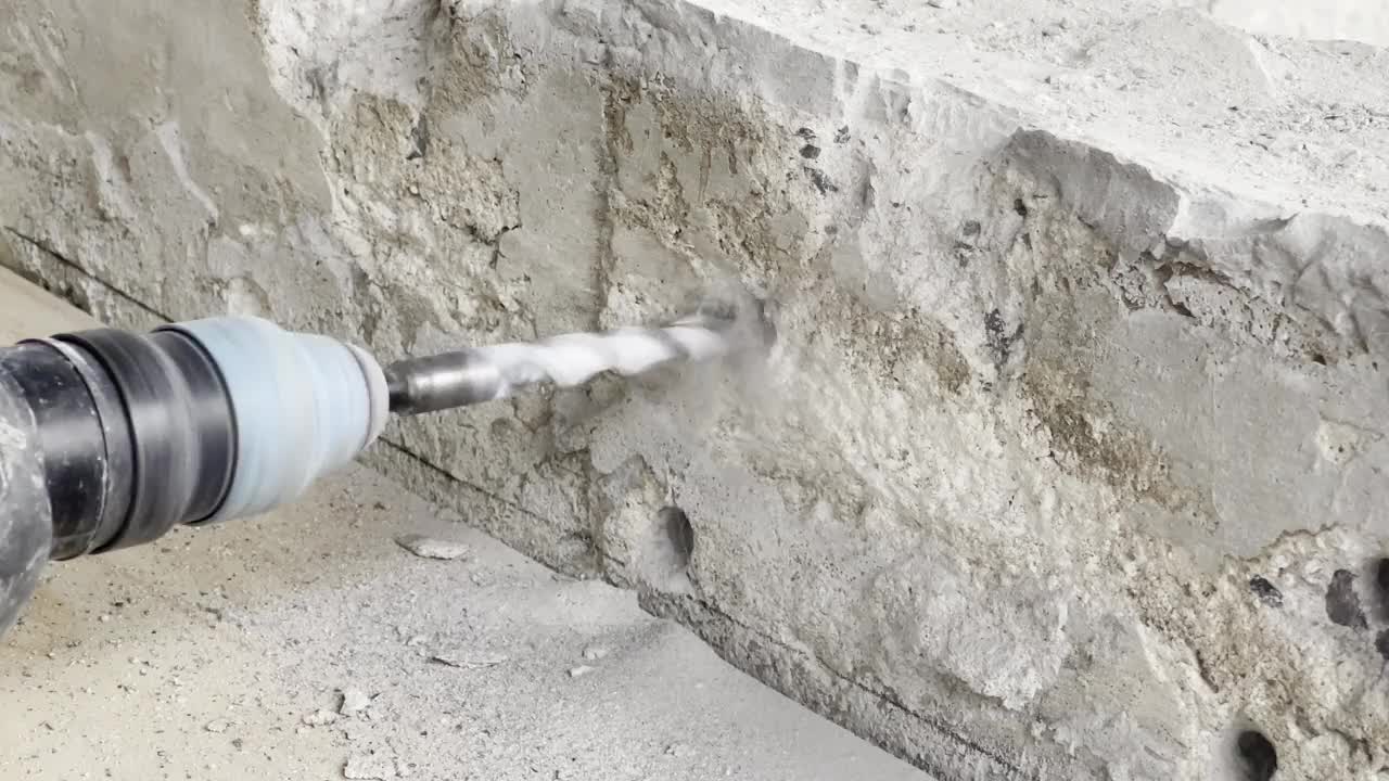 一个工人正在用钻头在砖石上钻孔。视频下载