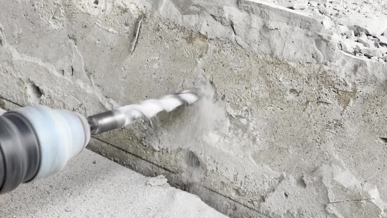 一个工人正在用钻头在砖石上钻孔。视频素材