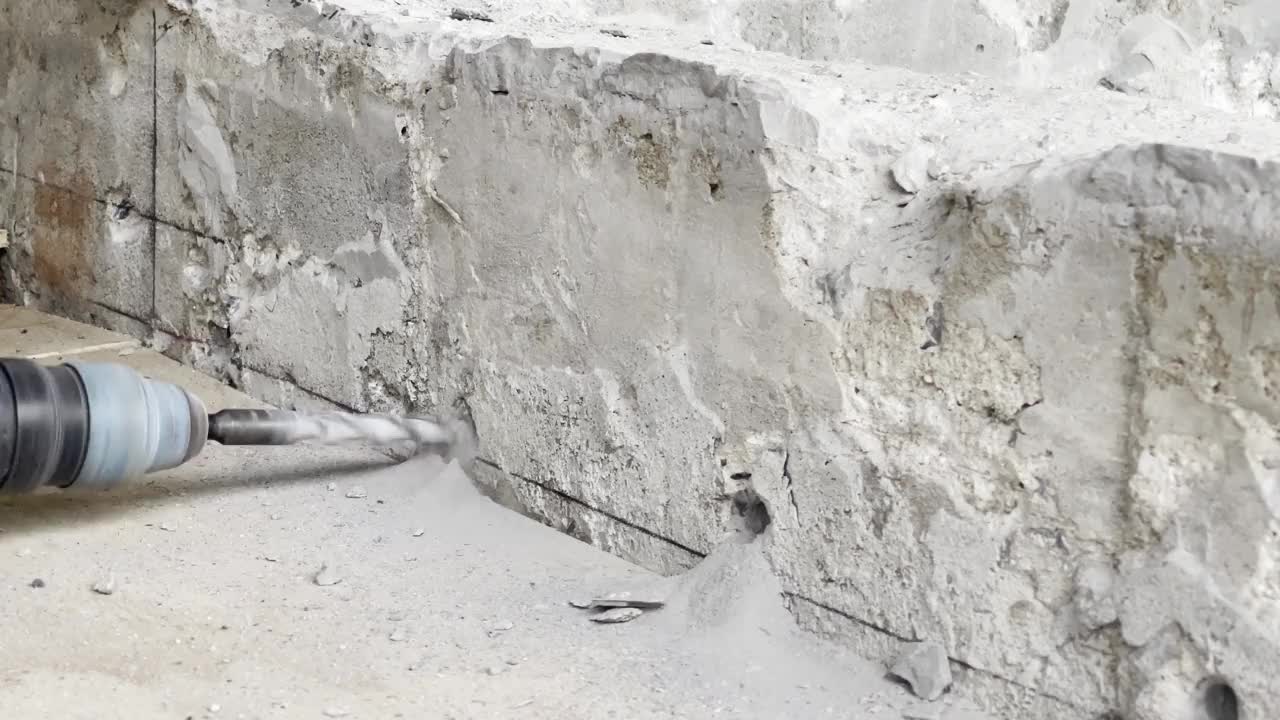 一个工人正在用钻头在砖石上钻孔。视频素材