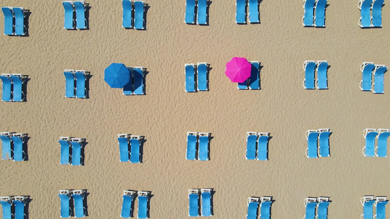 空沙滩上的空沙滩伞，4K分辨率，躺椅和海景的鸟瞰图，太阳躺椅伞，沙滩上的太阳躺椅和伞，空海滩和空太阳躺椅视频下载