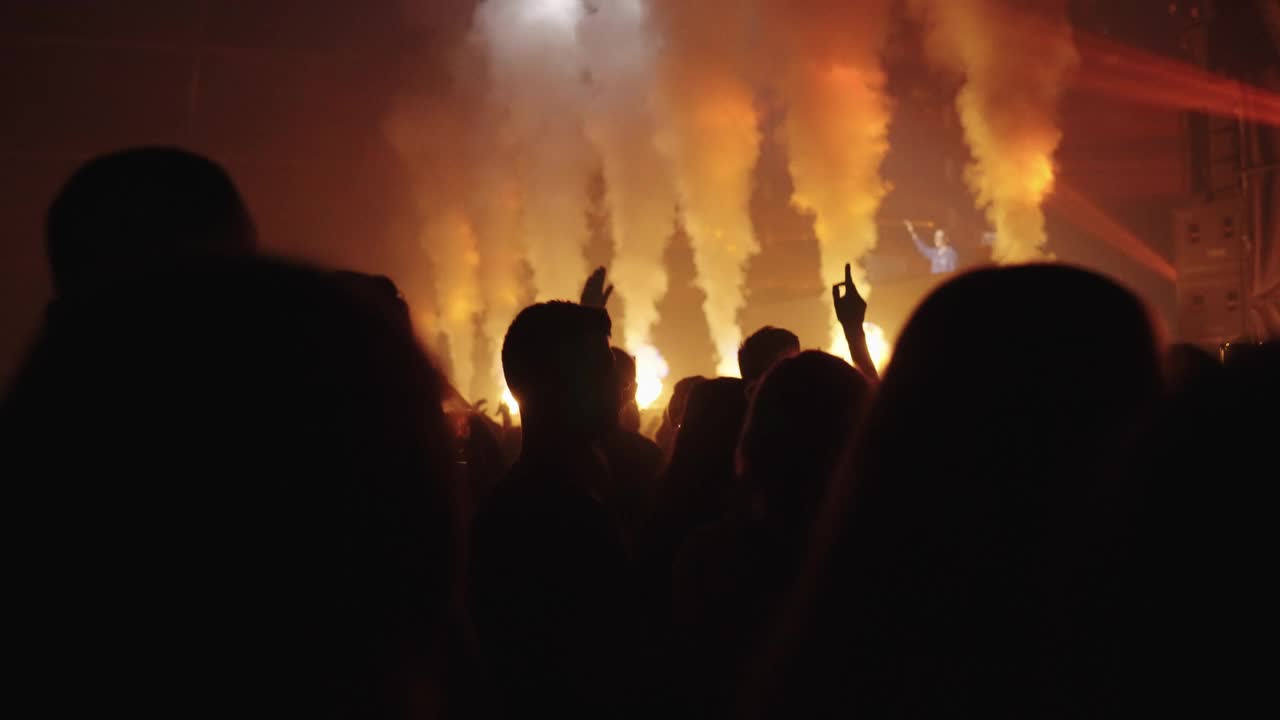 在音乐节上欢呼的人群。五颜六色的灯饰和烟雾。黑暗的舞台视频下载