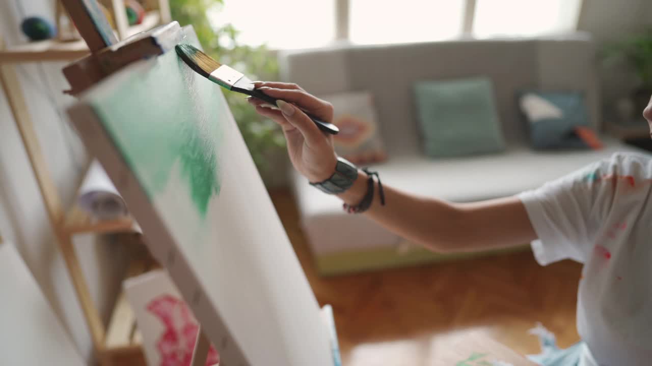 一个不知名的女艺术家用宽画笔在画布上作画的b卷视频下载