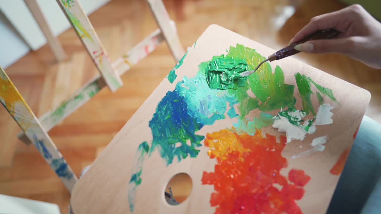 一个不知名的女艺术家用抹刀在调色板上混合丙烯颜料视频下载