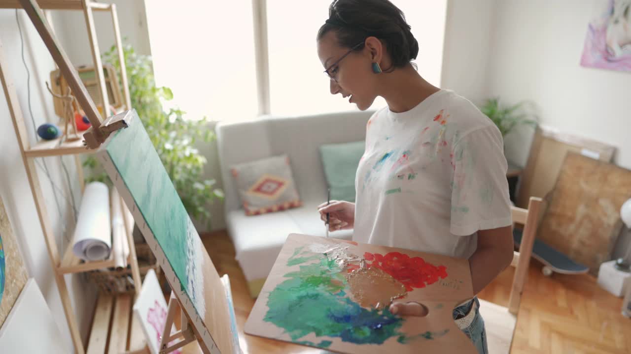 天才女画家用丙烯颜料在帆布上画大海和海滩视频下载