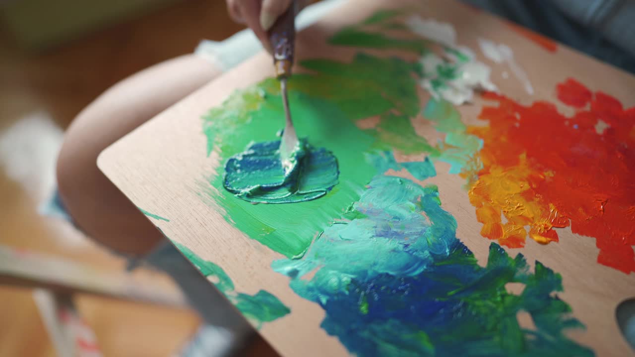 一个不知名的女艺术家用抹刀在调色板上混合丙烯颜料的b卷视频下载