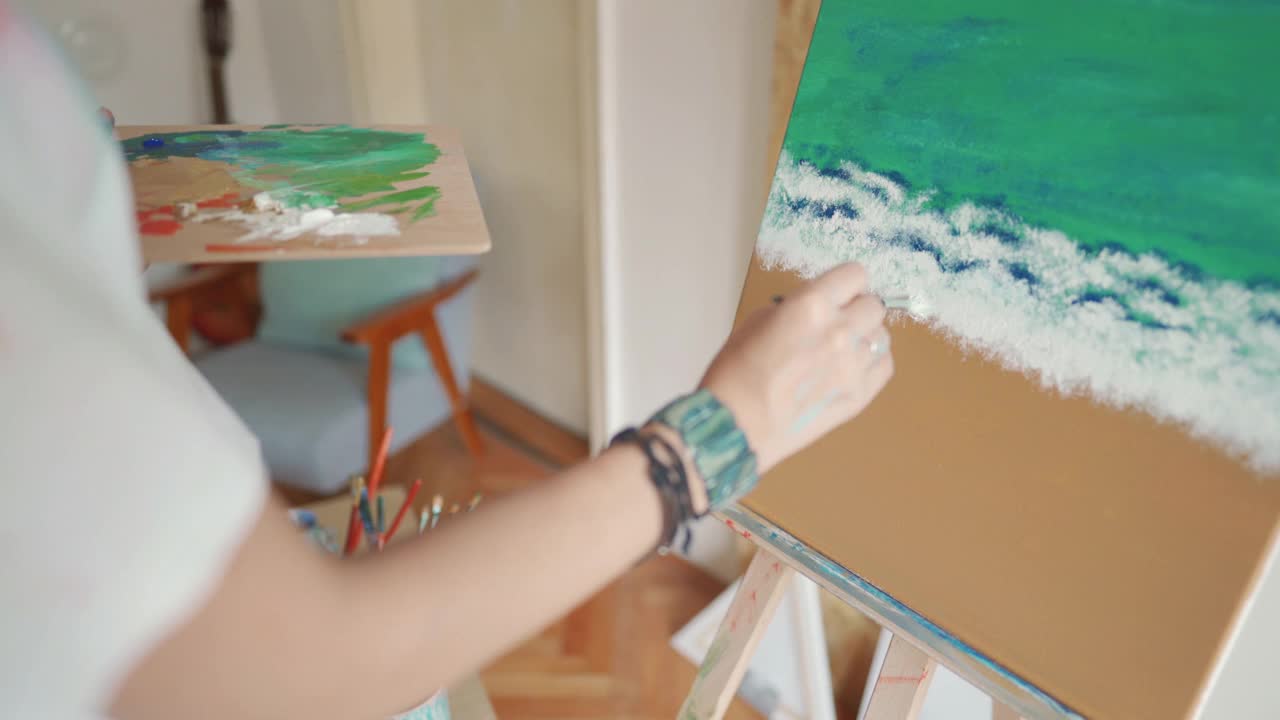 年轻的女艺术家，享受着她的业余爱好，在家里画一幅油画视频素材
