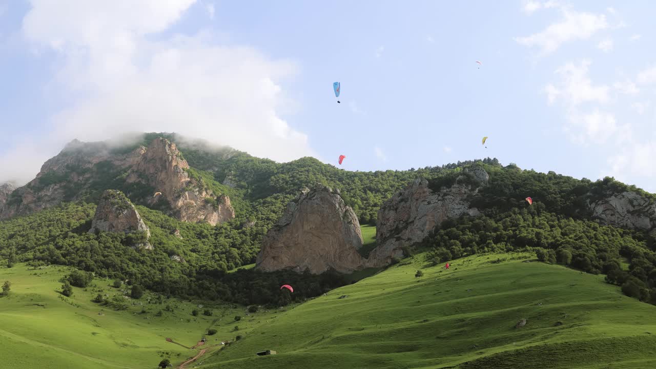 滑翔伞飞行员驾驶滑翔伞在云朵和青山之间飞行。视频素材