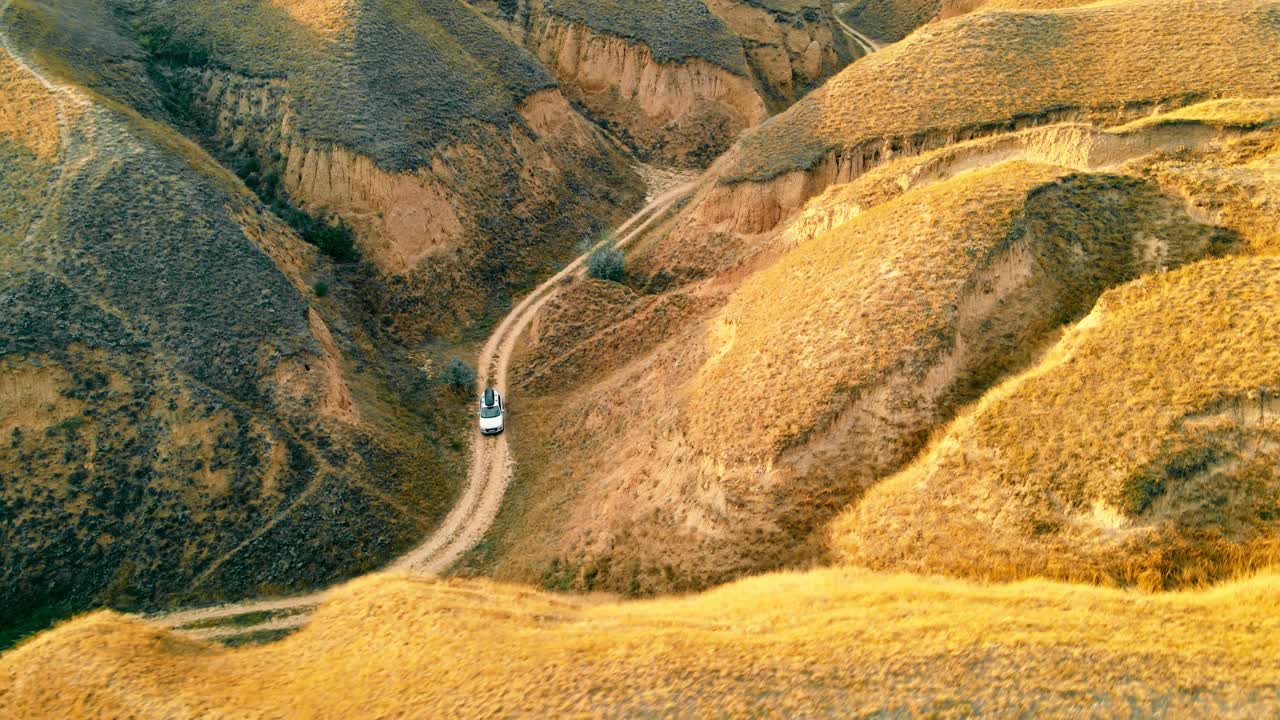 鸟瞰图汽车在峡谷中行驶在大沙山之间的土路上。国家公园里令人难以置信的峡谷景观视频素材