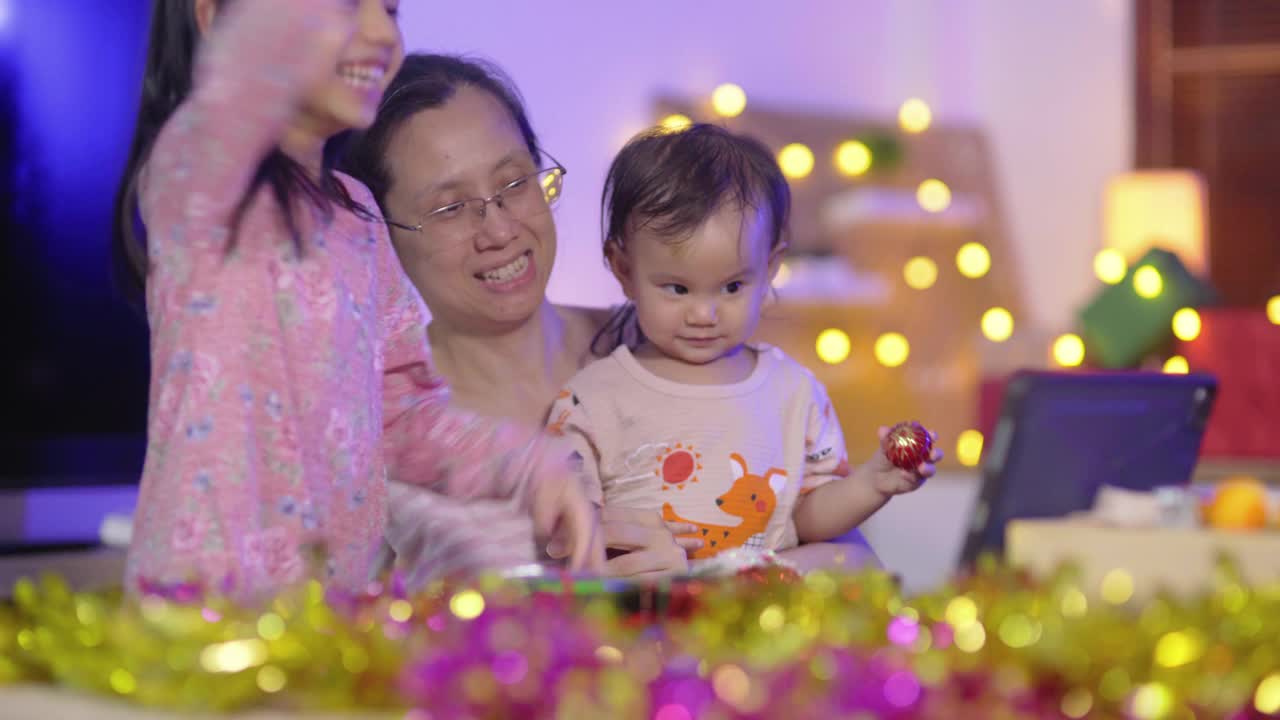 有两个孩子的亚洲家庭晚上坐在客厅里，和爷爷奶奶用电脑开会，周末花时间活动视频下载