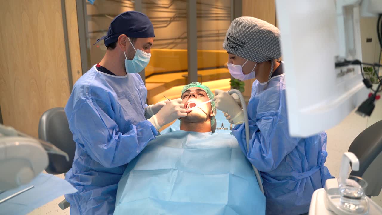 牙科团队戴着防护口罩、手套和面罩在牙科诊所进行牙科手术视频下载