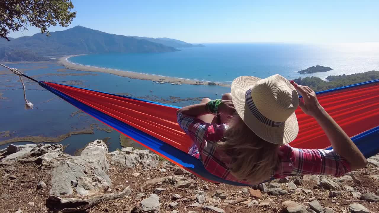 躺在吊床上的女人愉快地望着大海。视频下载