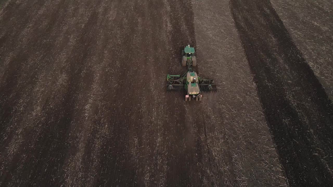鸟瞰图，绿色拖拉机与犁在田里工作的无人机视图，视频素材