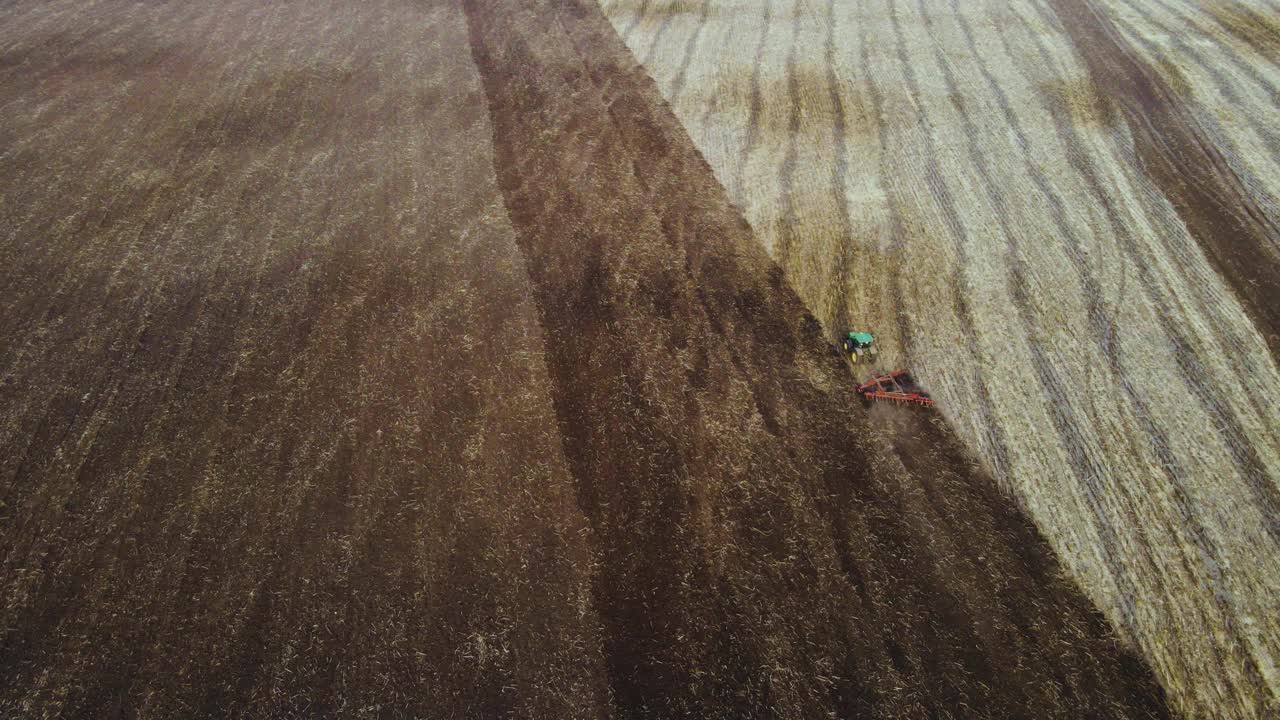 鸟瞰图，绿色拖拉机与犁在田里工作的无人机视图，视频素材