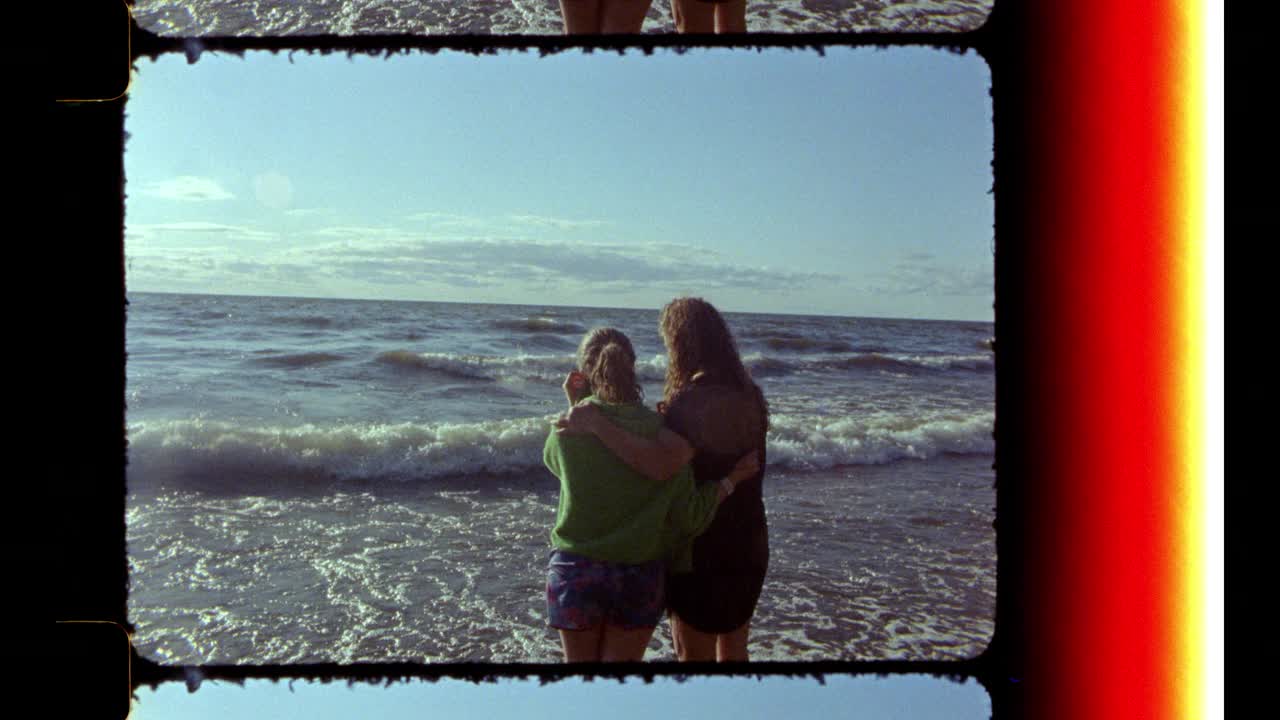 母女俩在海滩上对着镜头微笑。视频素材