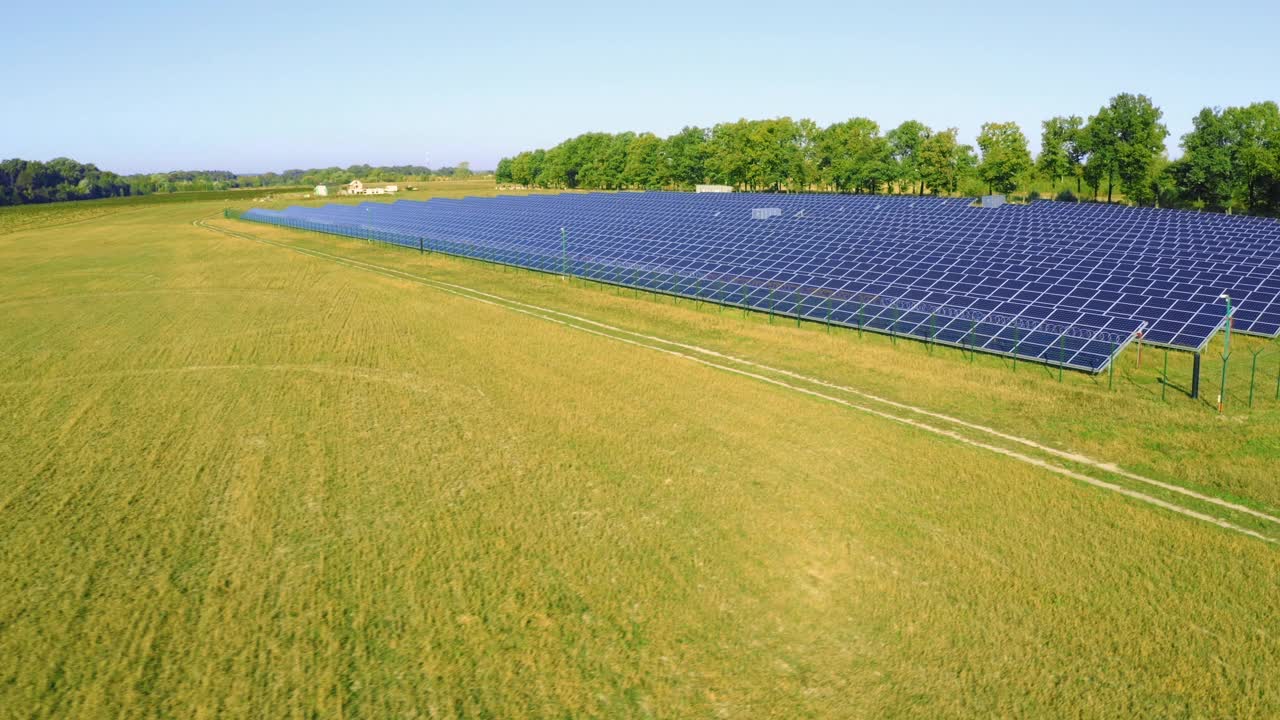 从鸟瞰图上看，阳光明媚的绿色田野里的太阳能电池板农场。视频下载