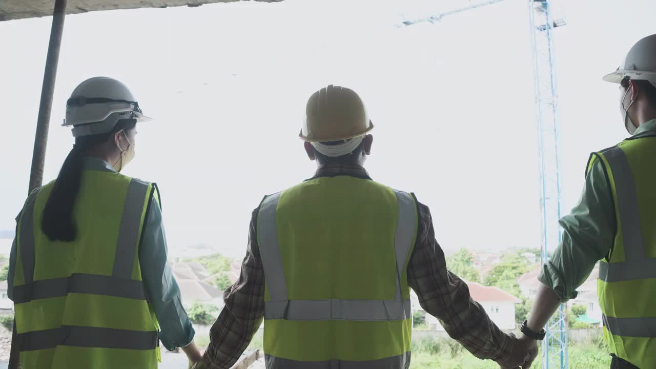 慢动作组工程师穿着反光背心和安全安全帽在建筑工地工作。建筑工程师作为一个工作团队一起工作。携手迈向成功。视频下载