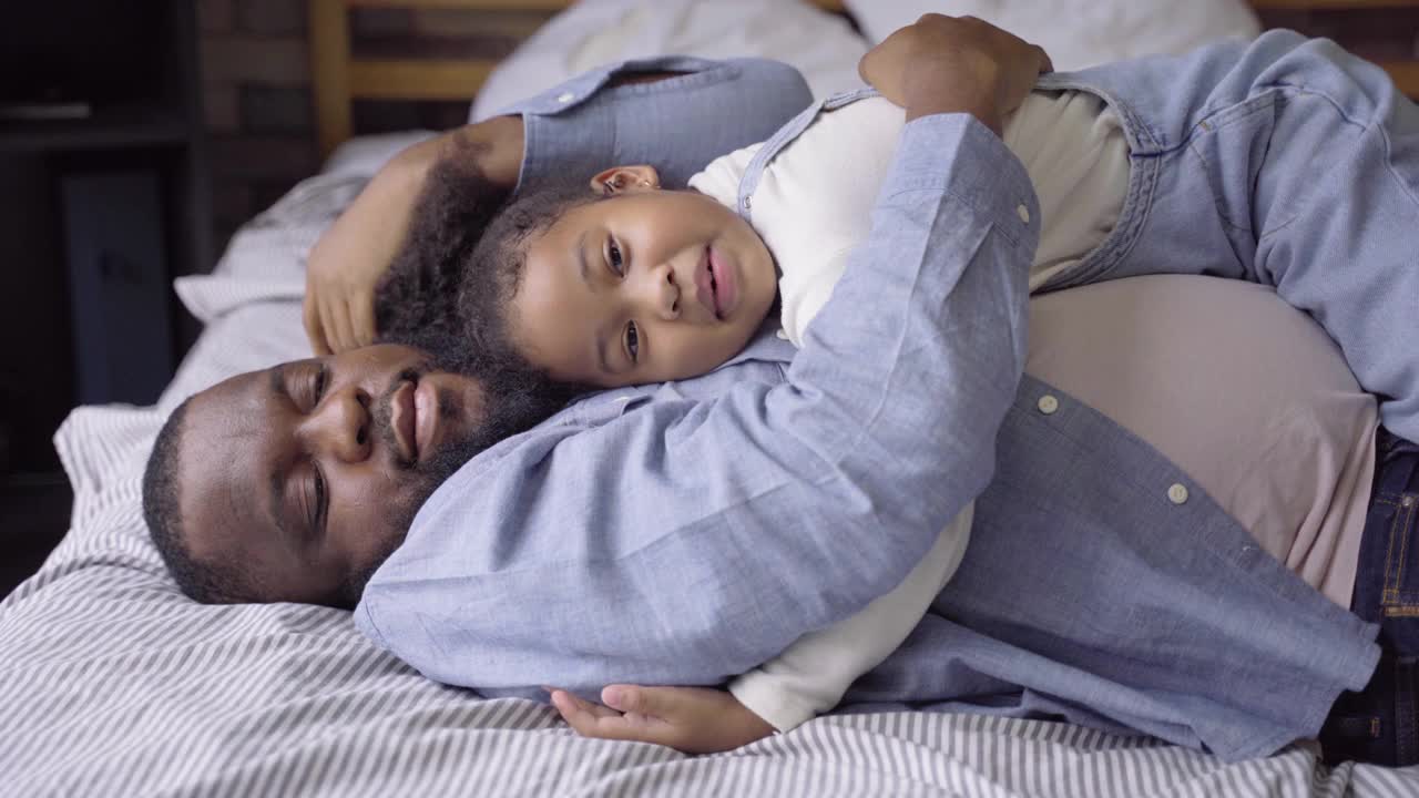 黑人父母喜欢和他们的女儿一起在家里欢笑和玩耍。假期的家庭放松时间视频素材