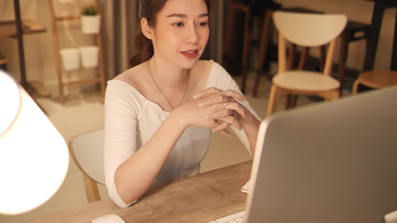 亚洲自由职业女性休闲装使用平板电脑工作电话视频会议与客户在工作场所，在家里的客厅。快乐年轻的亚洲女孩放松坐在桌子上做工作在互联网。视频素材