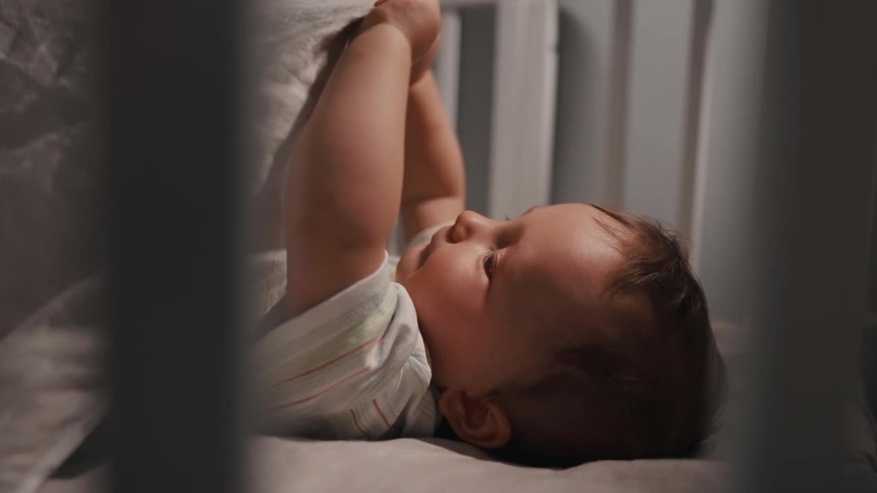 可爱的新生男婴，晚上不想睡在婴儿床上。妈妈把婴儿放到床上视频下载