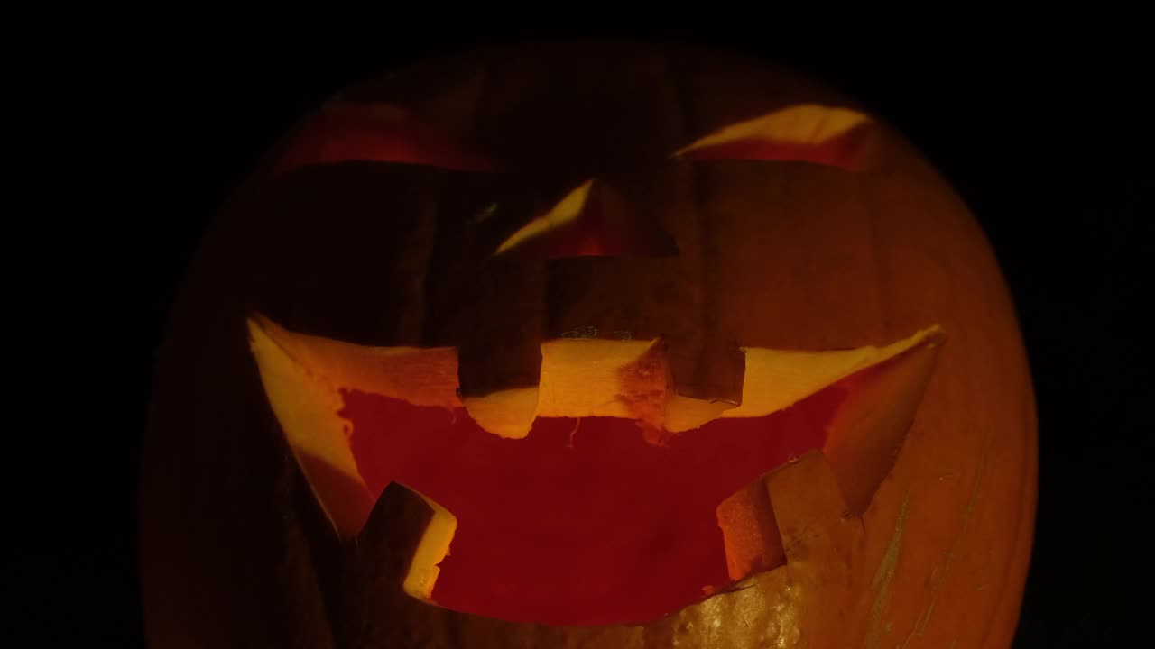 万圣节前夜龇牙咧嘴的南瓜在黑暗中发光。视频素材