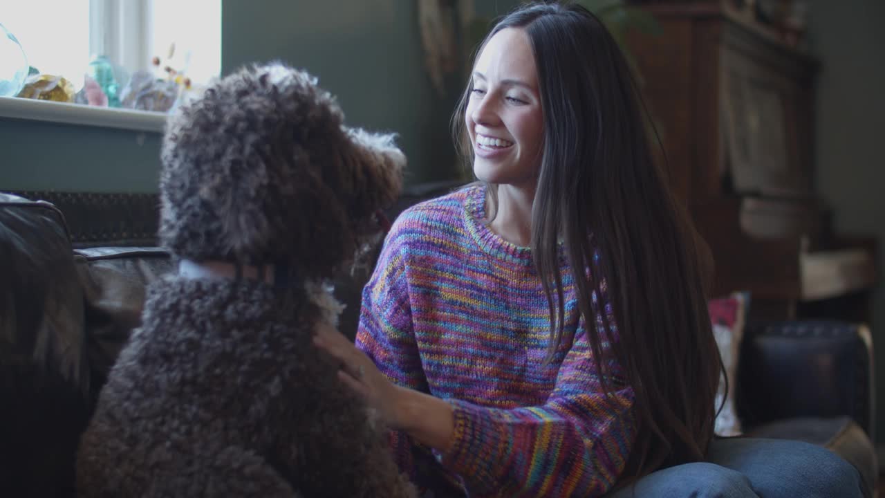 一个年轻漂亮的女人在家里和她的狗玩耍视频下载