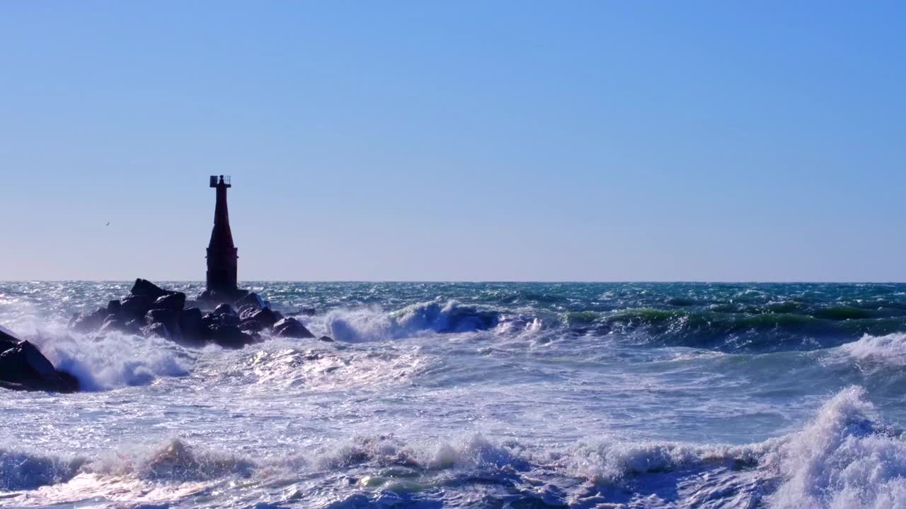 在海上风暴。海浪拍打着古老的灯塔和岩石，溅起了水花和泡沫。视频下载