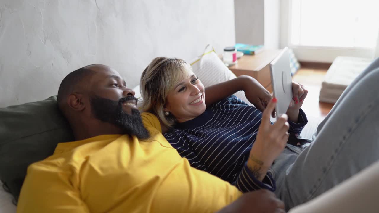 幸福的夫妇一起在家里的床上使用电子平板电脑视频下载