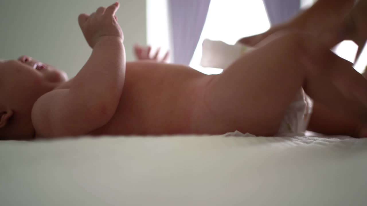 亚洲母亲在床上给孩子换尿布视频下载