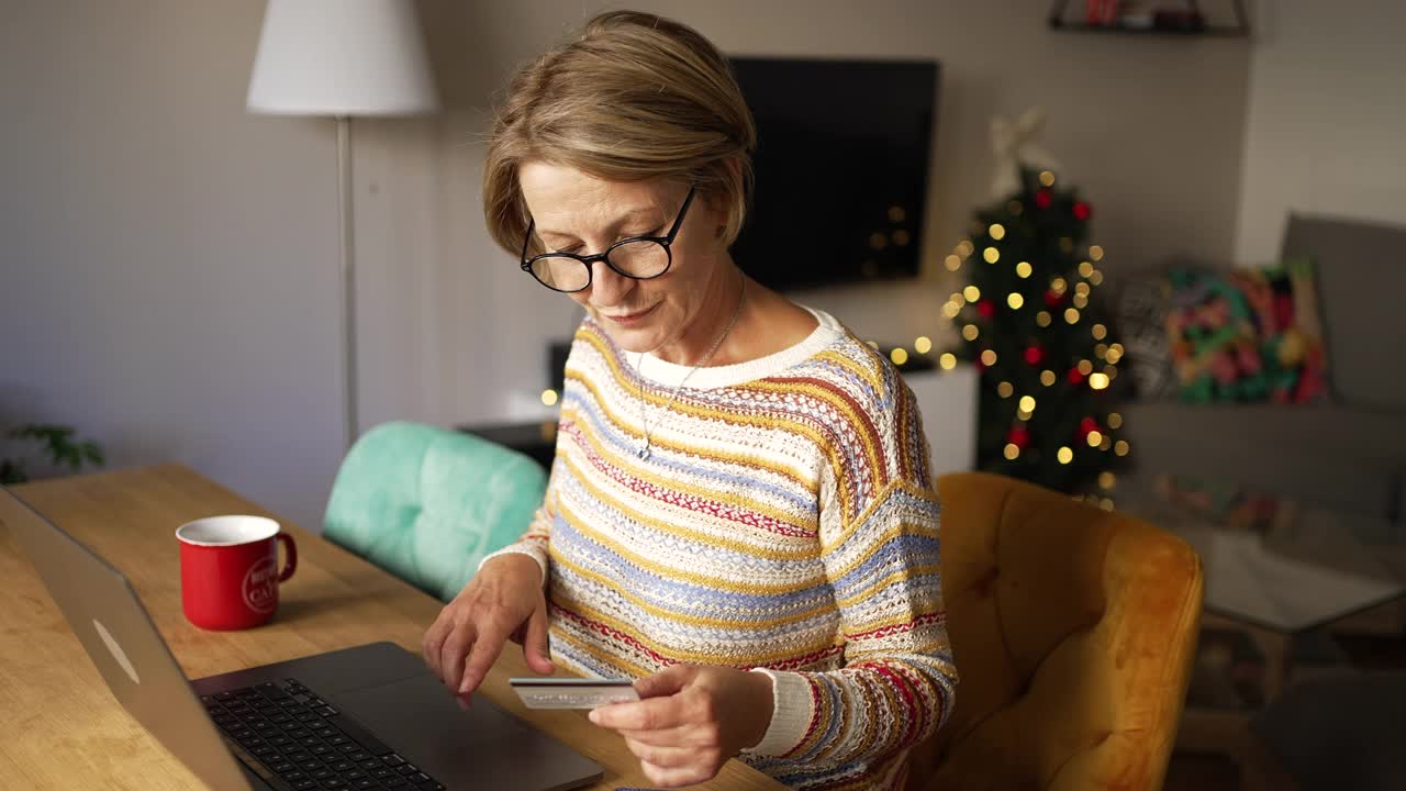 一个成熟的女人一边在网上圣诞购物一边输入信用卡信息视频下载
