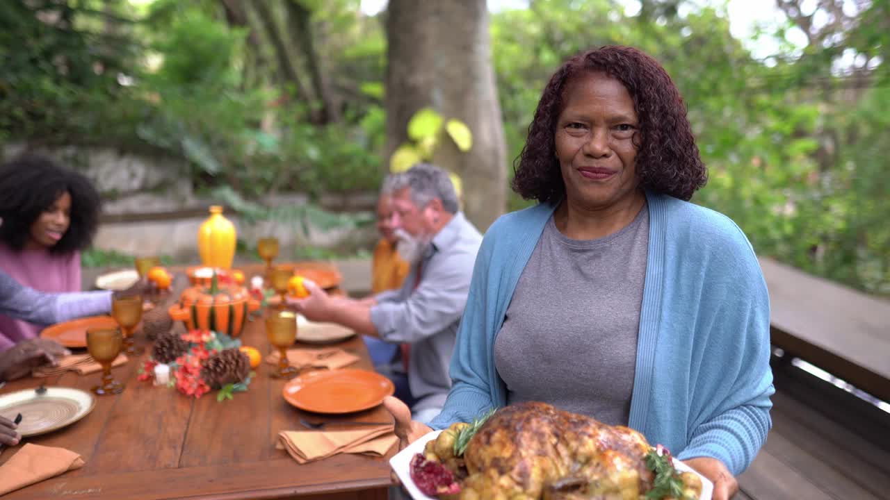 一位年长妇女的肖像，她在家里为感恩节举着烤火鸡视频下载