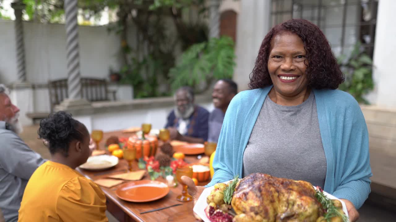 一位年长妇女的肖像，她在家里为感恩节举着烤火鸡视频下载
