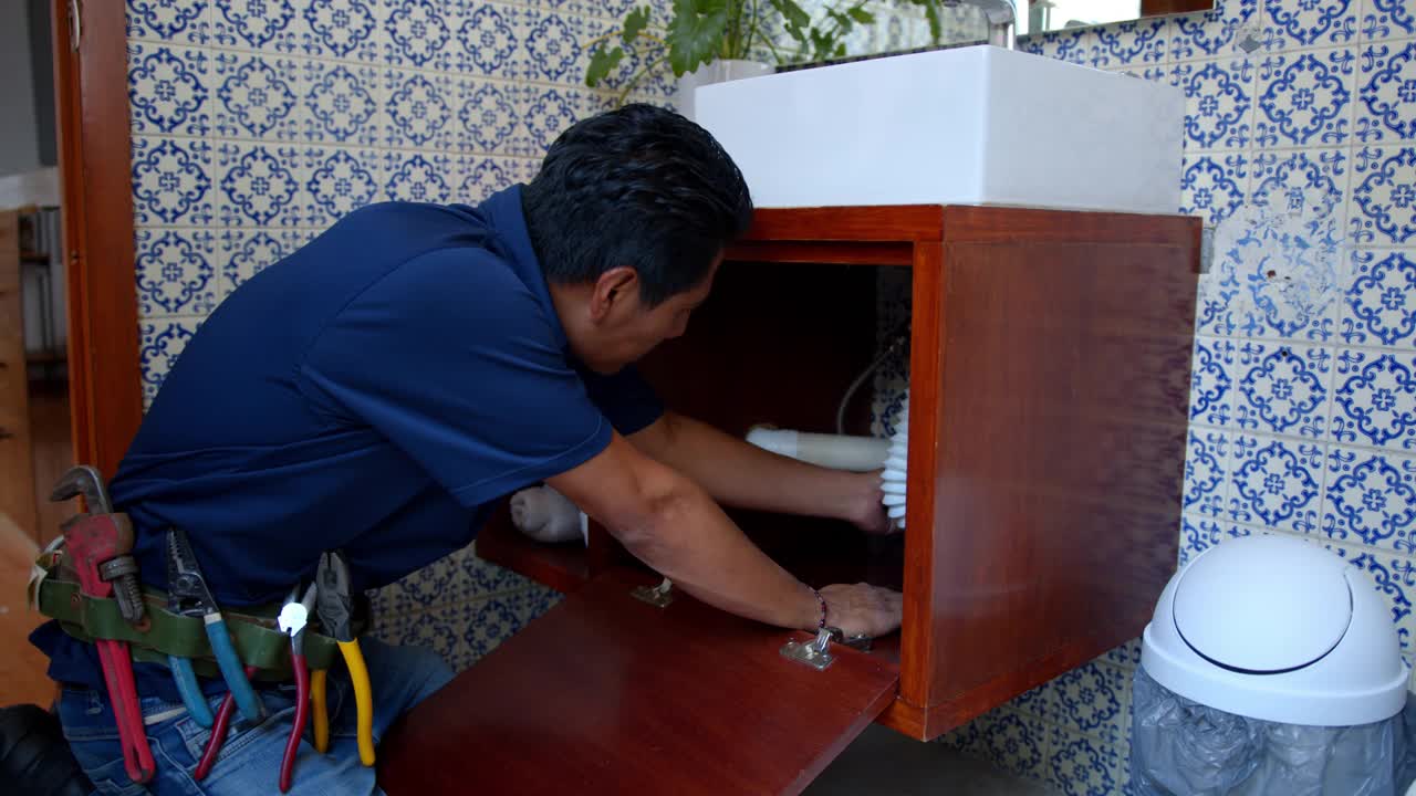 拉丁美洲的水管工正在修理水槽浴室的漏水视频素材