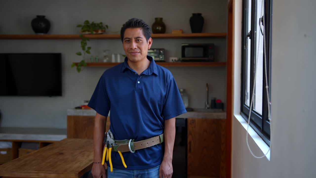 快乐的拉丁美洲电工工作在一个房子看着摄像机微笑着双臂交叉视频下载