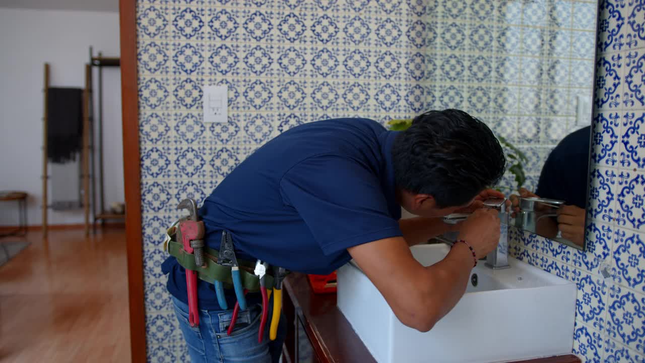 拉丁美洲的水管工正在客户家中修理浴室的水槽龙头视频素材
