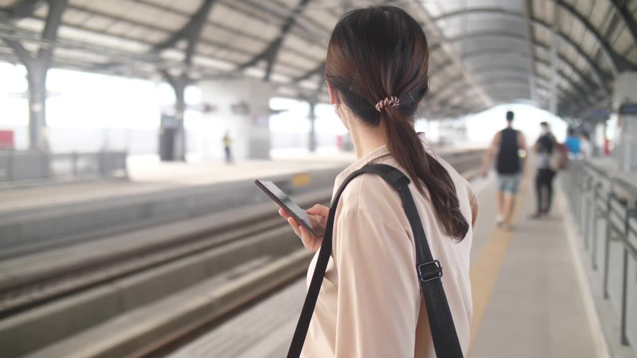 一名女子在曼谷火车站用智能手机等车视频下载