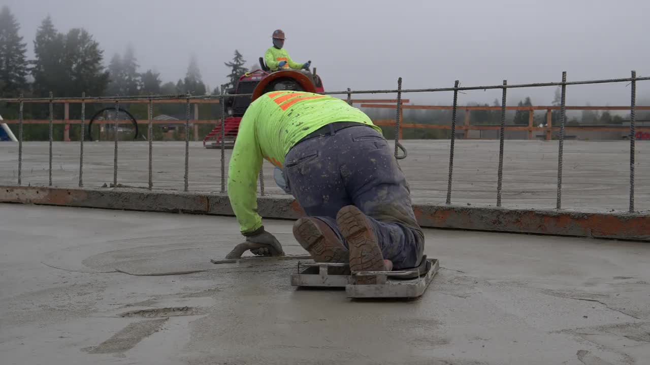 建筑工人在一个大型商业工地拖拽刚浇好的混凝土。视频素材