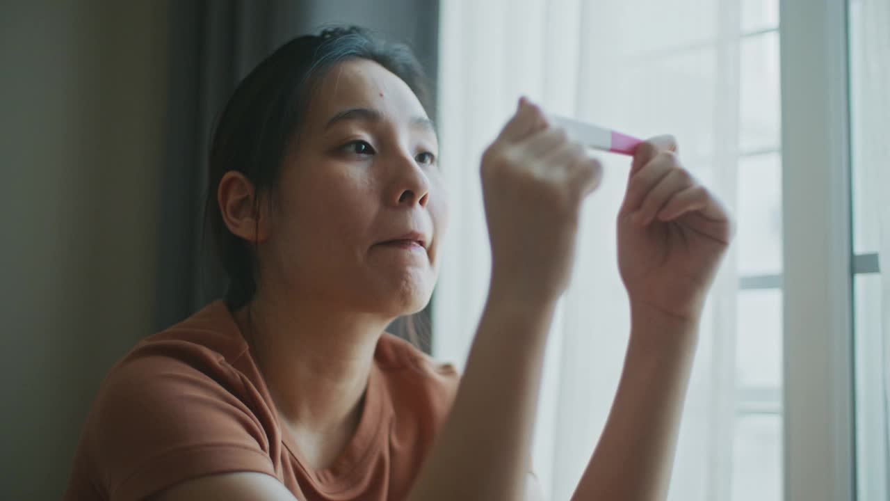 快乐的亚洲妇女在检查妊娠试验阳性结果后感到快乐视频下载