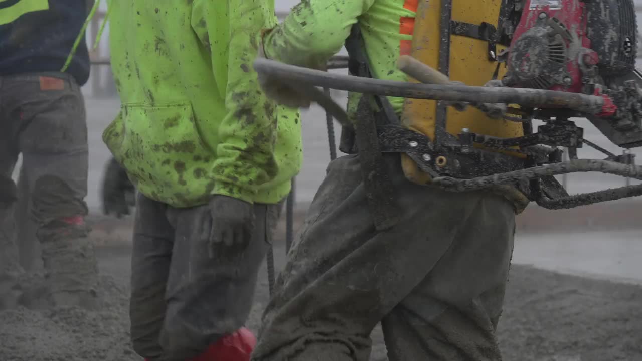 在一个大型商业工地，一名建筑工人在水泥浇筑过程中启动混凝土振动器。视频素材