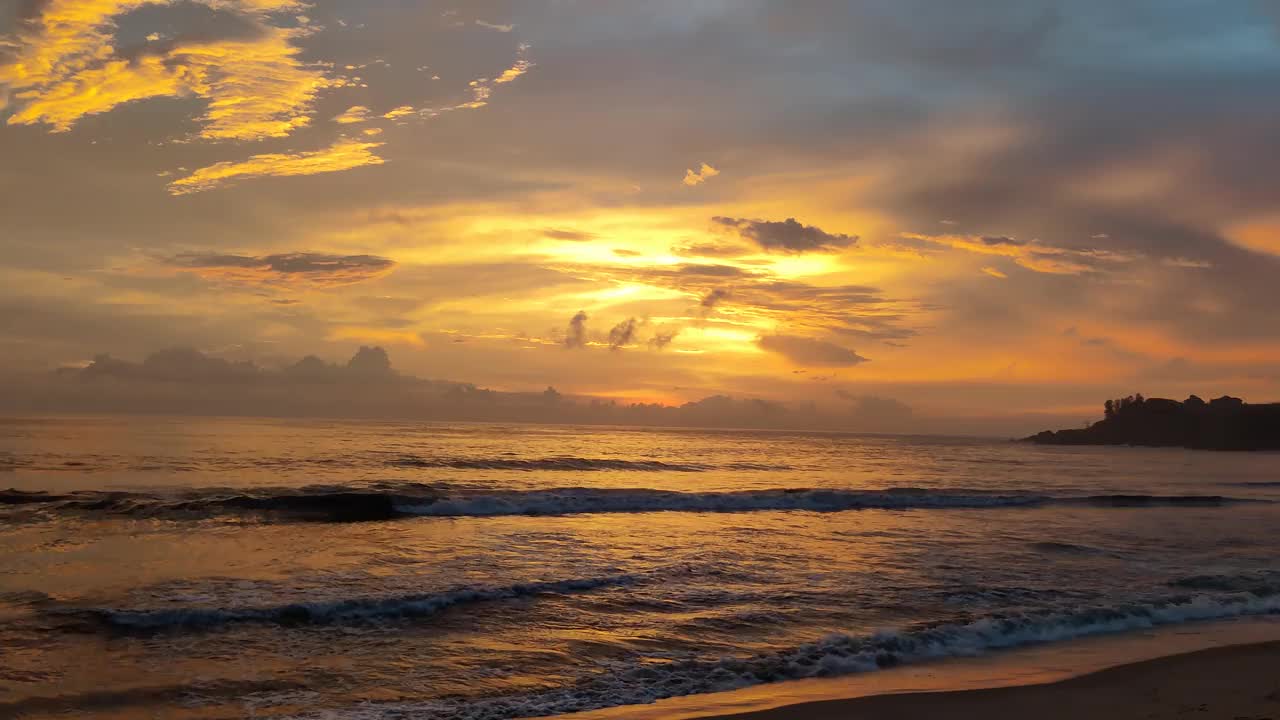 美丽的傍晚橙色的日落与云彩之上的海浪从海滩视频素材