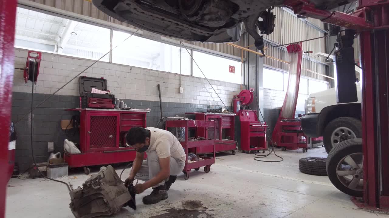 拉丁美洲墨西哥普埃布拉的一名男性机械师，正在清洗车间地板上的引擎部件视频下载