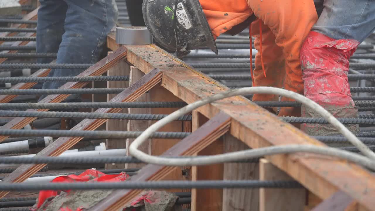 在一个大型商业工地，建筑工人正在为混凝土浇筑准备钢筋。视频素材