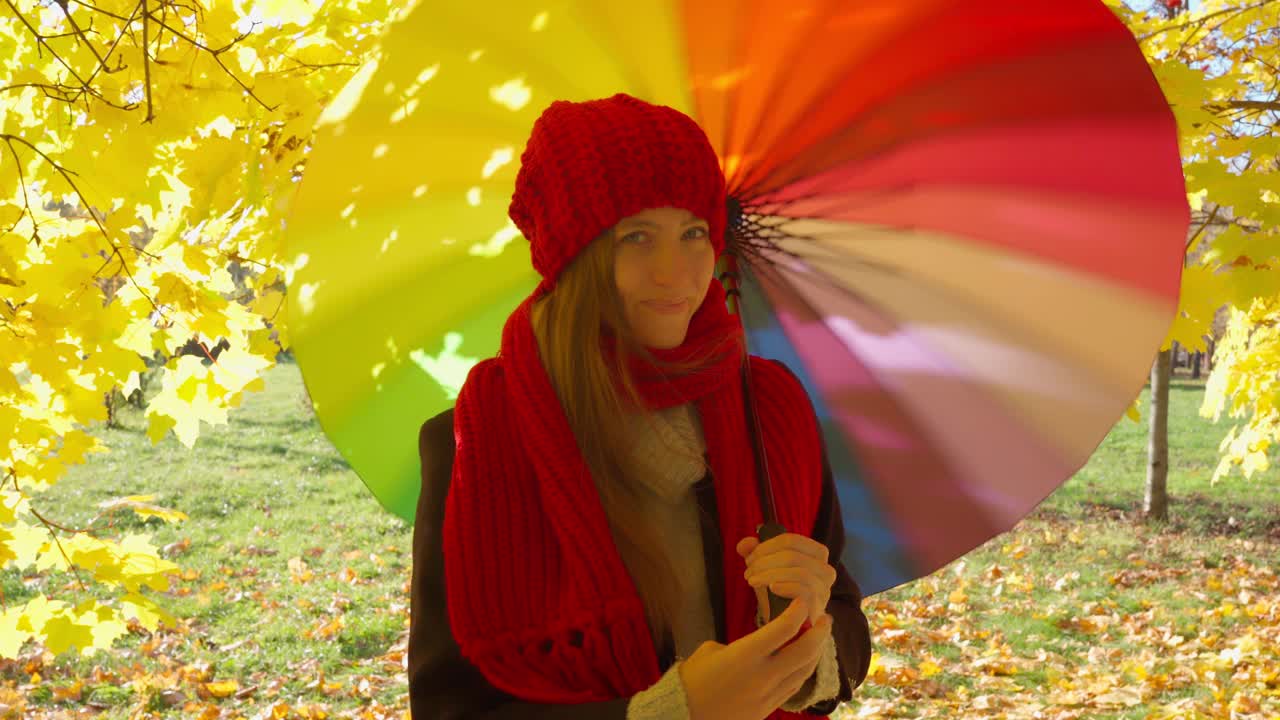 美丽快乐的女人打着伞站在公园里微笑。阳光明媚的视频素材
