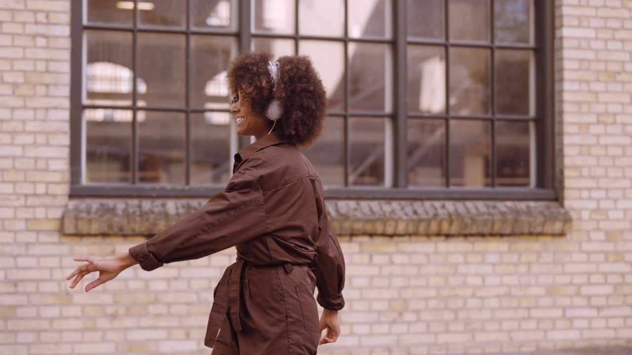 跳舞的女人戴着耳机在街上听音乐视频下载