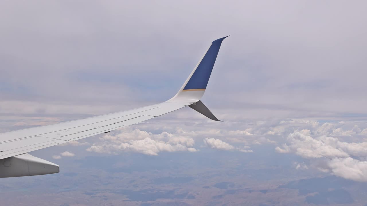 蓝天上的云朵，用飞机的翅膀从舷窗往下看视频素材