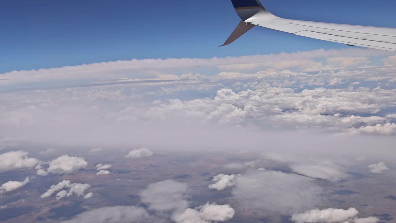 飞行旅行的视野从飞机的机翼上的窗户上的云蓝色的天空视频素材