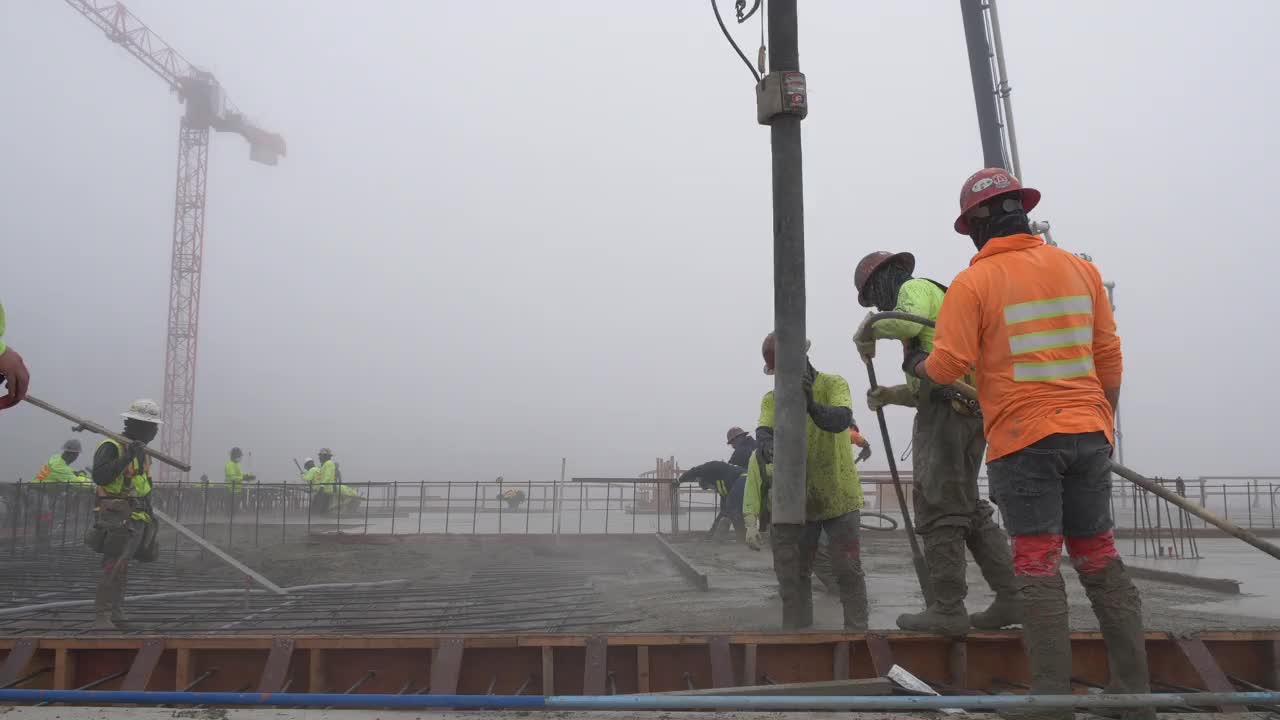 一组建筑工人在一个大型商业工地使用泵吊浇注混凝土。视频素材