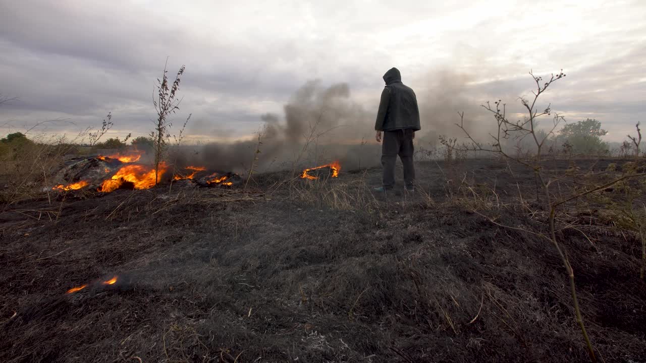 一个人站在草原上燃烧的田野上视频素材